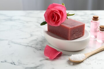 Soap bars, cosmetic products and beautiful rose on white marble table, closeup. Space for text