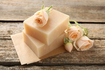 Soap bars and beautiful roses on wooden table, closeup