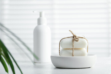Soap bars and bottle on white table indoors, selective focus