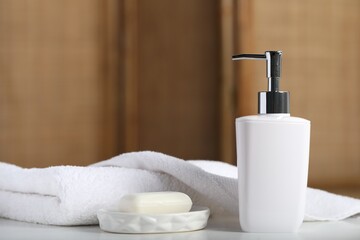 Soap bar, bottle of cosmetic product and towels on white table indoors