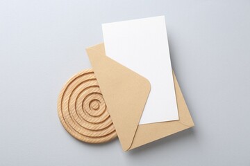 Blank invitation card and envelope on light grey background, top view
