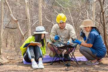 A group of scientists are studying a rock sample in the field.