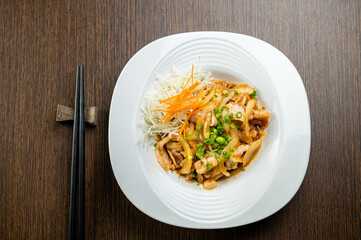 A plate of delicious Japanese food with pork, cabbage, and carrots.