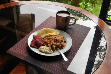 Gallo pinto, a typical Costa Rican dish with rice, red beans, sausage, cream, and a fried egg, and a glass of coffee.