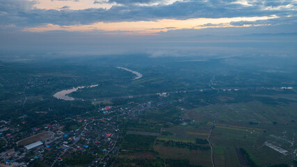 A stunning aerial view of a winding river flowing through a vast rural landscape at dawn. The soft morning light and misty atmosphere create a tranquil and picturesque scene, with scattered villages