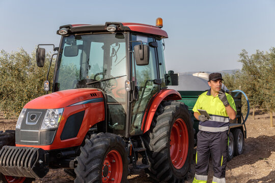 Tractor operator talking on walkie-talkie managing agricultural tasks on olive farm