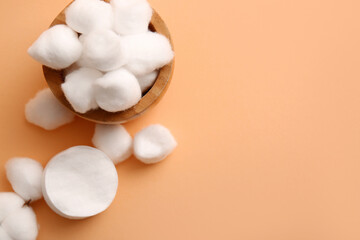 Wooden bowl with cotton balls and pads on brown background