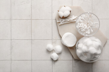Glasses with cotton balls, swabs, pads and flower on white tile background