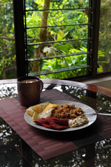 Gallo pinto, a typical Costa Rican dish with rice, red beans, sausage, cream, and a fried egg, and a glass of coffee.