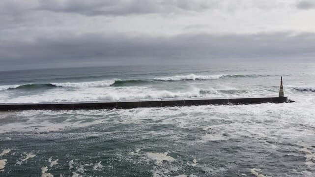 Huge waves crashing over Breakwater during winter storm Atlantic waves washing the lighthouse on Praia da Aguda sandy beach at Aguda settlement near Porto, Portugal. Incredible 4K flying drone video.