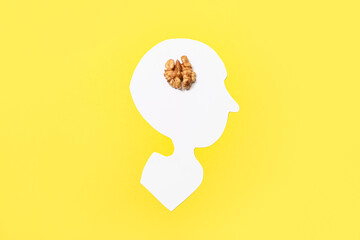 Paper human head with walnut on yellow background