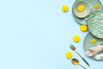 Stylish table setting with beautiful dandelion flowers on blue background