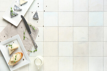 Plate with fresh bread, triangles of tasty processed cheese and micro green on light tile table