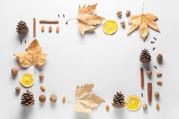 Frame made of fallen leaves, spices, pine cones and dried orange slices on grey background
