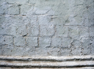 Fototapeta premium Monochrome antique stone wall with uneven texture. The rectangular blocks are visible through the rough plaster. Copy space.