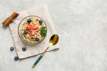 Bowl with tasty oatmeal, berries and mint leaves on grey grunge background