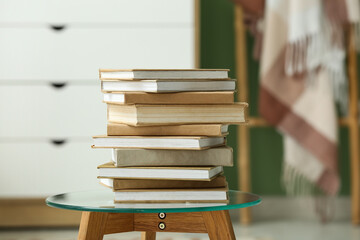 Stack of books on glass coffee table in living room, closeup
