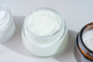 close up of collagen cream in open glass jar on marble background. Presentation of skin care beauty...