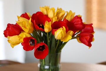 Beautiful tulips in vase on wooden table indoors, closeup
