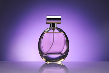 Bottle of perfume on mirror surface against purple gradient background
