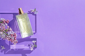 Flat lay composition with bottle of perfume and lilac flowers on violet background. Space for text
