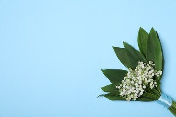 Beautiful lily-of-the-valley flowers on light blue background, top view. Space for text