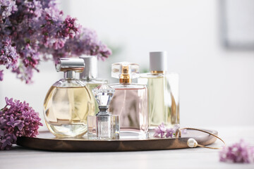 Bottles of perfumes and lilac flowers on white wooden table