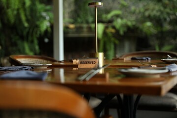Sign with word Reserved on wooden table in restaurant