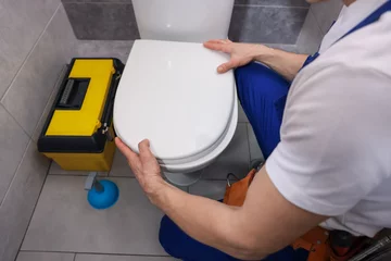 Gordijnen Professional plumber repairing toilet bowl in restroom, closeup © New Africa