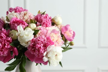Bouquet of beautiful peonies in vase indoors, closeup. Space for text