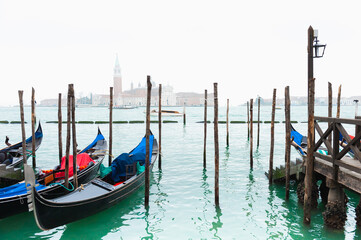 Fototapeta premium Gondolas on the Grand canal at foggy sunset in Venice, Italy. San Giorgio Maggiore Cathedral in the background.