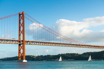 25th April Bridge over the Tejo river in Lisbon, Portugal. Yachts sailing on the river