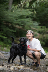 川で遊ぶ大型犬と飼い主　夏は川であそぶ暑がりなカメラ目線の犬