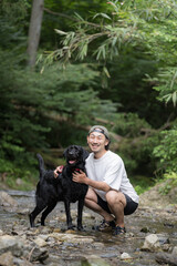 川で遊ぶ大型犬と飼い主　夏は川であそぶ暑がりなカメラ目線の犬