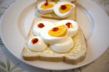 Bread and margarine with sliced egg and red gold sauce on plate.