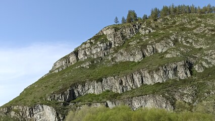 Rocky Mountain Slope with Green Vegetation and a Clear Blue Sky Backdrop. Nature Landscape