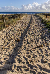 A sandy path to a beautiful beach in the early morning.
