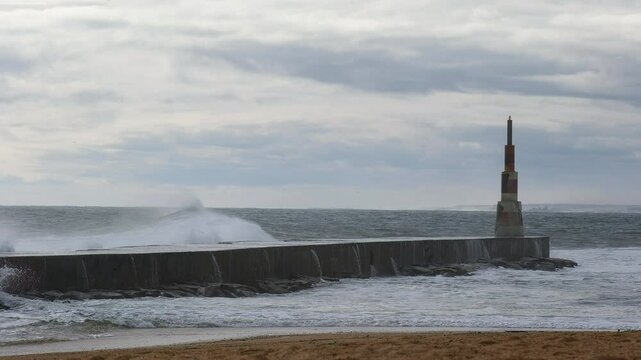 Huge waves crushing over Breakwater during winter storm Atlantic waves washing the lighthouse on Praia da Aguda sandy beach at Aguda settlement near Porto, Portugal.