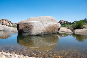 Cyclopean granite boulder in Tungabhadra river, water reflection, rocky terrain landscape, Hampi, South India, Karnataka