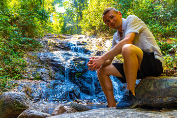 Man male tourist at Ton Chongfa Waterfall tropical jungle Thailand.