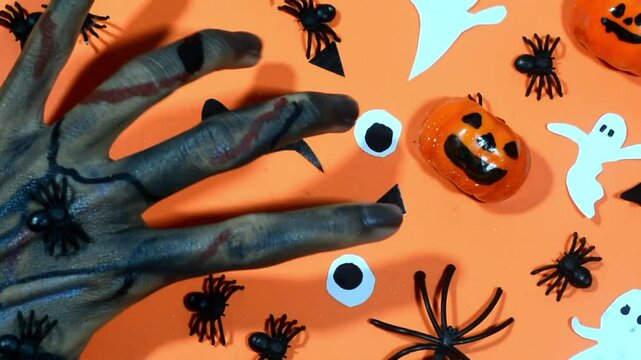 Halloween frame with party decorations of pumpkins, bats, ghosts, spiders on orange background from above. Happy halloween card in flat lay style.