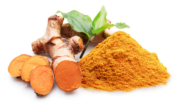 Turmeric rhizome slices, turmeric powder and green leaves on white background. File contains clipping path.
