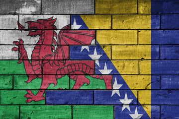 Obraz premium colourful painted big national flag of wales and flag of bosnia and herzegovina on a massive old brick wall background. concept