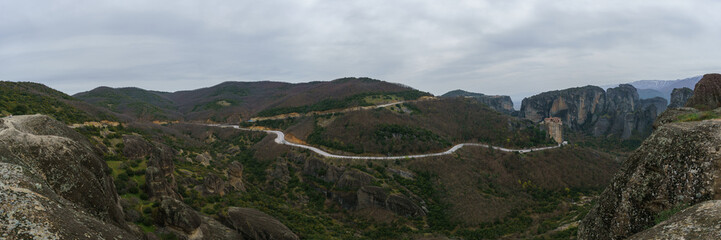 Panoramic view of country road at rock formations Meteora with Monasteries Roussanou and Holy Trinity on top of the rocks, Kalambaka, Thessaly, Greece