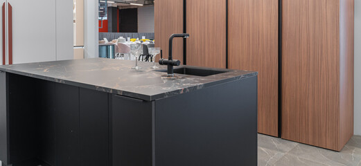 modern built-in kitchen. kitchen island with black marble countertop, black faucet and sink. modern...