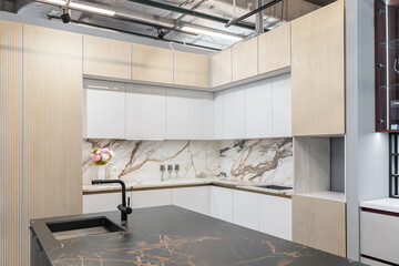 large corner built-in kitchen in white and beige shades. Modern kitchen with upper and lower...