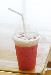 Pink iced milk on a wooden table at cafe