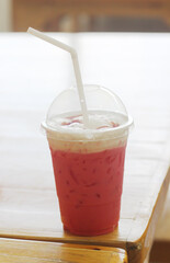 Pink iced milk on a wooden table at cafe