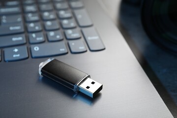 USB flash drive and laptop on dark grey table, closeup