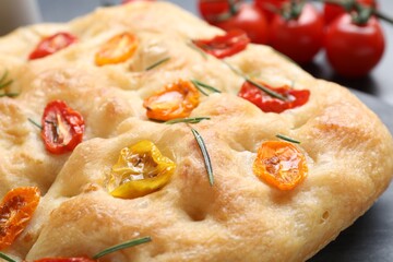 Delicious focaccia with tomatoes and rosemary on table, closeup